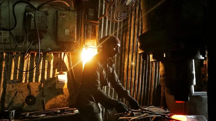 Worker operating a hydraulic press machine at a manufacturing workshop in Mumbai